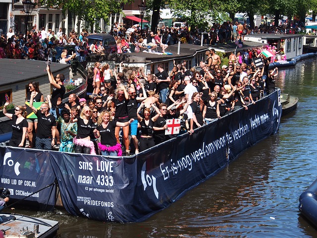Uitbundig feestende mensen op een boot op de Prinsengracht tijdens de Gay Pride in Amsterdam. Het spandoek op de boot zegt: 'Er is nog veel om voor te vechten'