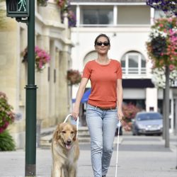 Blinde vrouw steekt de straat over met hulp van een blindengeleidehond